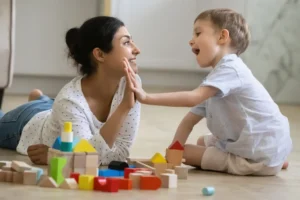 Woman and child playing with colorful building blocks on the floor