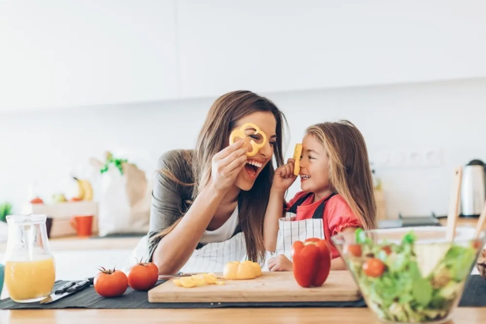  Mother and daughter having fun with vegetables in the kitchen