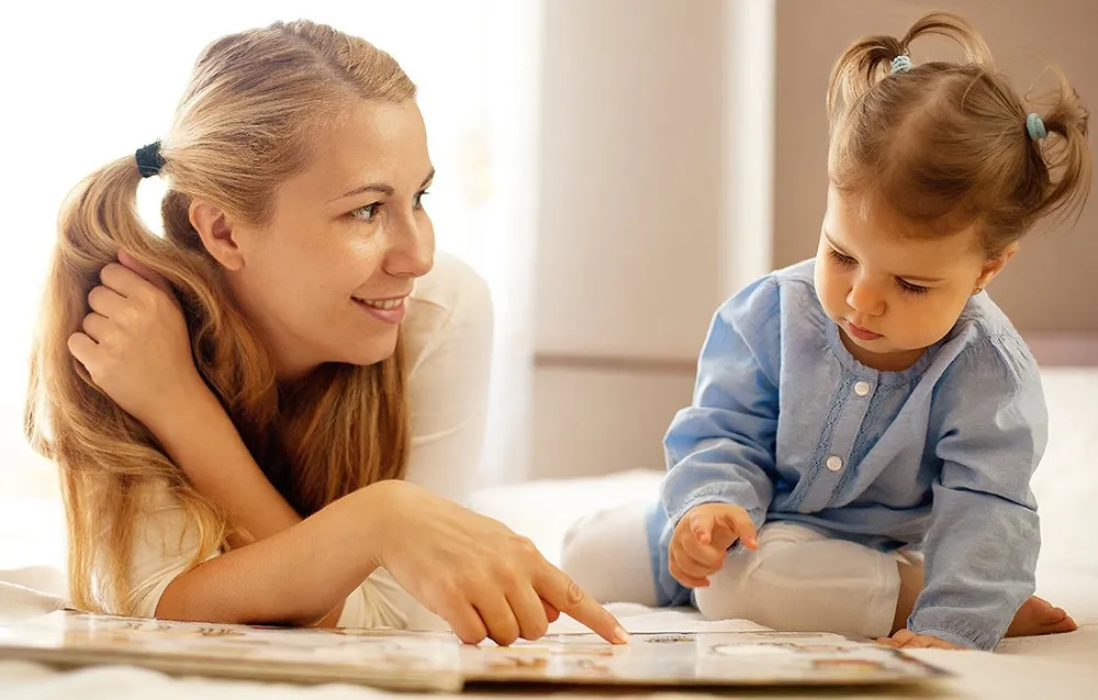 Mother and child reading a book together indoors.