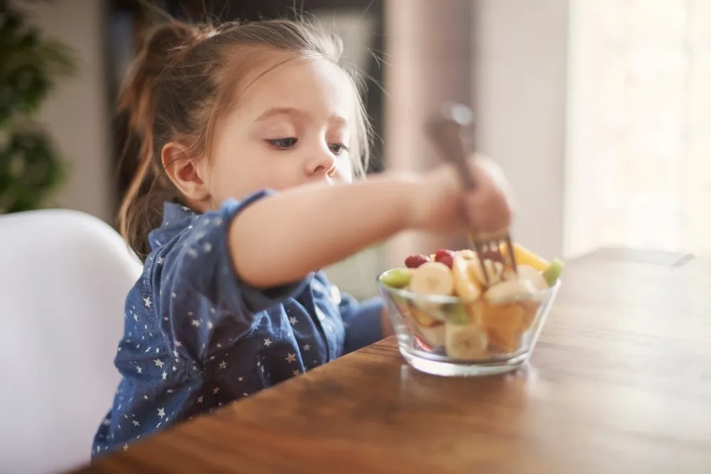 Child enjoying a fruit salad at home