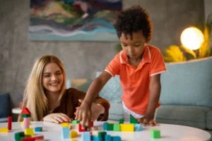 Woman and child playing with colorful building blocks on a table.
