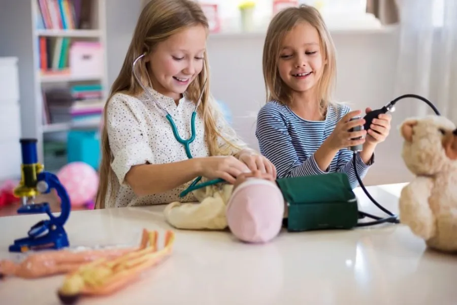 Children playing doctor with toys and stuffed animals indoors