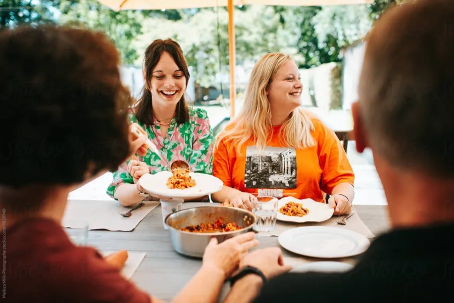 Family enjoying a meal together outdoors under a sunny umbrella