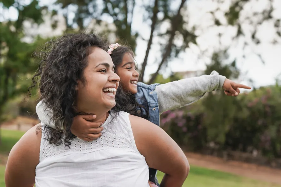 Mother and daughter smiling and pointing in a park